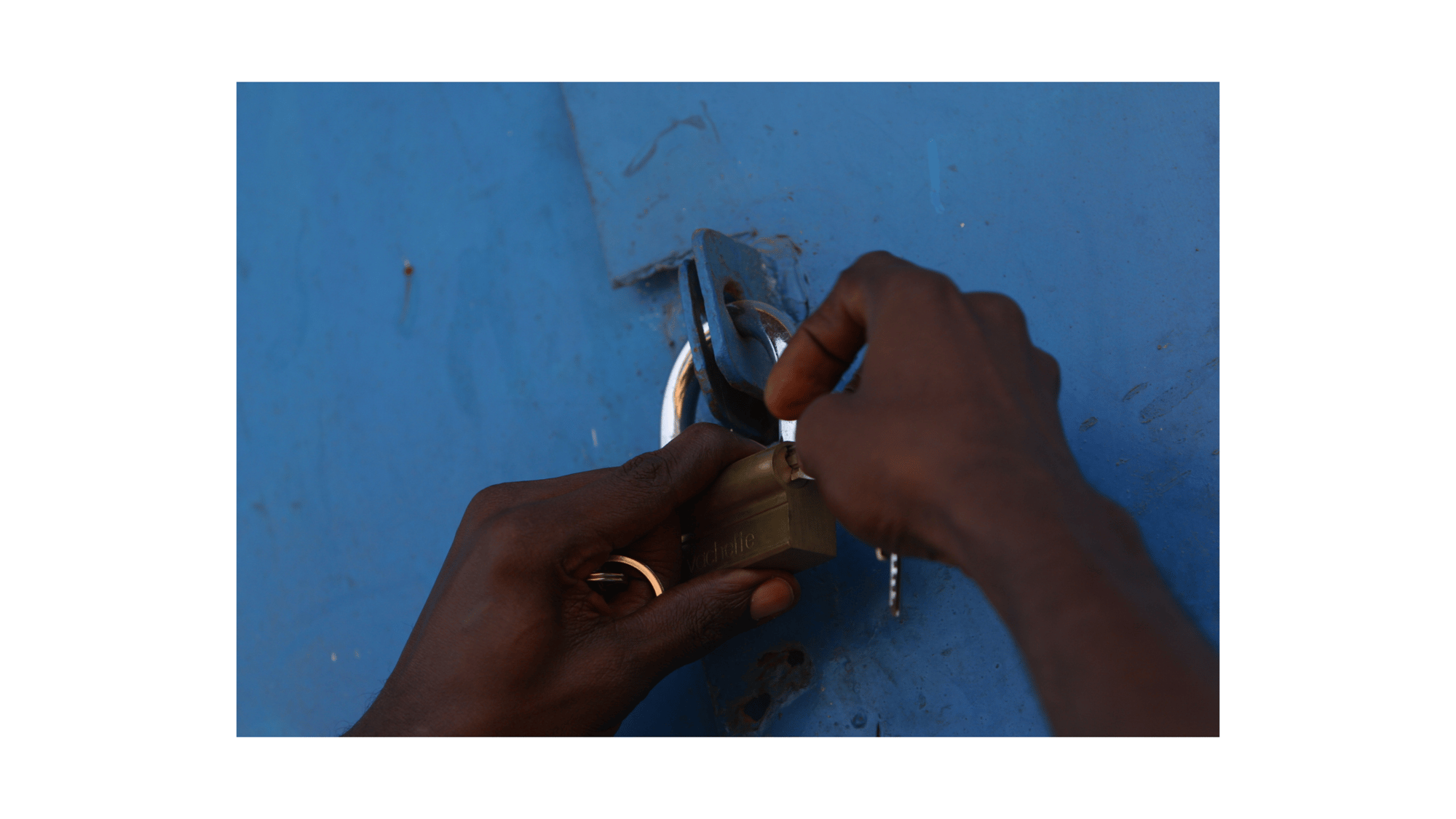 Dark hands undoing padlock